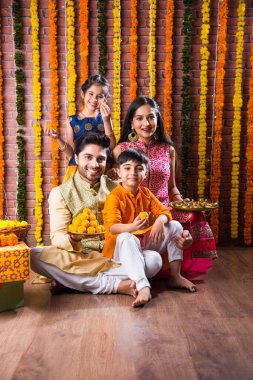 Diwali veya Rakshabandhan Kutlaması - Dört kişilik Hint ailesi Deepavali veya Bhai Dooj festivalini tatlı laddoo, yağ lambası ve şeker ve şeker kutuları ile kutluyor, yemek yiyor veya selfie çekiyor