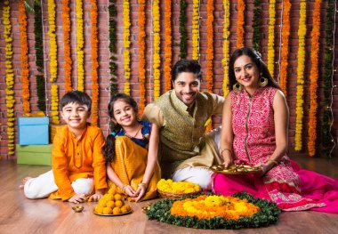 Diwali veya Rakshabandhan Kutlaması - Dört kişilik Hint ailesi Deepavali veya Bhai Dooj festivalini tatlı laddoo, yağ lambası ve şeker ve şeker kutuları ile kutluyor, yemek yiyor veya selfie çekiyor