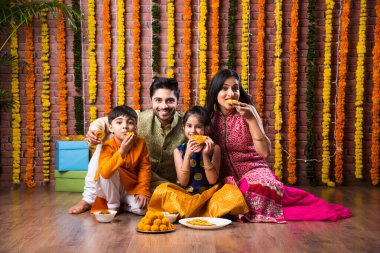 Diwali veya Rakshabandhan Kutlaması - Dört kişilik Hint ailesi Deepavali veya Bhai Dooj festivalini tatlı laddoo, yağ lambası ve şeker ve şeker kutuları ile kutluyor, yemek yiyor veya selfie çekiyor