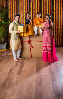 Diwali veya Rakshabandhan Kutlaması - Dört kişilik Hint ailesi Deepavali veya Bhai Dooj festivalini tatlı laddoo, yağ lambası ve şeker ve şeker kutuları ile kutluyor, yemek yiyor veya selfie çekiyor