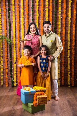 Diwali veya Rakshabandhan Kutlaması - Dört kişilik Hint ailesi Deepavali veya Bhai Dooj festivalini tatlı laddoo, yağ lambası ve şeker ve şeker kutuları ile kutluyor, yemek yiyor veya selfie çekiyor
