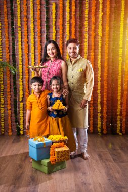 Diwali veya Rakshabandhan Kutlaması - Dört kişilik Hint ailesi Deepavali veya Bhai Dooj festivalini tatlı laddoo, yağ lambası ve şeker ve şeker kutuları ile kutluyor, yemek yiyor veya selfie çekiyor
