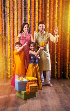 Diwali veya Rakshabandhan Kutlaması - Dört kişilik Hint ailesi Deepavali veya Bhai Dooj festivalini tatlı laddoo, yağ lambası ve şeker ve şeker kutuları ile kutluyor, yemek yiyor veya selfie çekiyor