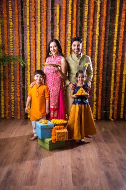 Diwali veya Rakshabandhan Kutlaması - Dört kişilik Hint ailesi Deepavali veya Bhai Dooj festivalini tatlı laddoo, yağ lambası ve şeker ve şeker kutuları ile kutluyor, yemek yiyor veya selfie çekiyor