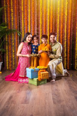 Diwali veya Rakshabandhan Kutlaması - Dört kişilik Hint ailesi Deepavali veya Bhai Dooj festivalini tatlı laddoo, yağ lambası ve şeker ve şeker kutuları ile kutluyor, yemek yiyor veya selfie çekiyor