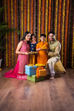 Diwali veya Rakshabandhan Kutlaması - Dört kişilik Hint ailesi Deepavali veya Bhai Dooj festivalini tatlı laddoo, yağ lambası ve şeker ve şeker kutuları ile kutluyor, yemek yiyor veya selfie çekiyor