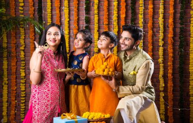 Diwali veya Rakshabandhan Kutlaması - Dört kişilik Hint ailesi Deepavali veya Bhai Dooj festivalini tatlı laddoo, yağ lambası ve şeker ve şeker kutuları ile kutluyor, yemek yiyor veya selfie çekiyor