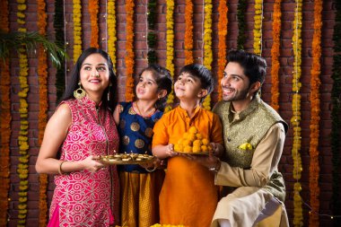 Diwali veya Rakshabandhan Kutlaması - Dört kişilik Hint ailesi Deepavali veya Bhai Dooj festivalini tatlı laddoo, yağ lambası ve şeker ve şeker kutuları ile kutluyor, yemek yiyor veya selfie çekiyor