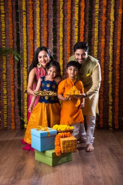 Diwali veya Rakshabandhan Kutlaması - Dört kişilik Hint ailesi Deepavali veya Bhai Dooj festivalini tatlı laddoo, yağ lambası ve şeker ve şeker kutuları ile kutluyor, yemek yiyor veya selfie çekiyor