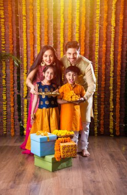 Diwali veya Rakshabandhan Kutlaması - Dört kişilik Hint ailesi Deepavali veya Bhai Dooj festivalini tatlı laddoo, yağ lambası ve şeker ve şeker kutuları ile kutluyor, yemek yiyor veya selfie çekiyor