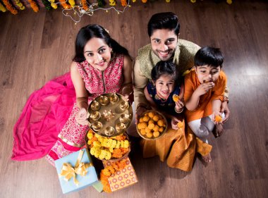 Diwali veya Rakshabandhan Kutlaması - Dört kişilik Hint ailesi Deepavali veya Bhai Dooj festivalini tatlı laddoo, yağ lambası ve şeker ve şeker kutuları ile kutluyor, yemek yiyor veya selfie çekiyor