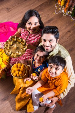 Diwali veya Rakshabandhan Kutlaması - Dört kişilik Hint ailesi Deepavali veya Bhai Dooj festivalini tatlı laddoo, yağ lambası ve şeker ve şeker kutuları ile kutluyor, yemek yiyor veya selfie çekiyor