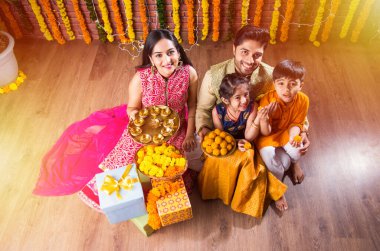 Diwali veya Rakshabandhan Kutlaması - Dört kişilik Hint ailesi Deepavali veya Bhai Dooj festivalini tatlı laddoo, yağ lambası ve şeker ve şeker kutuları ile kutluyor, yemek yiyor veya selfie çekiyor