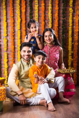 Diwali veya Rakshabandhan Kutlaması - Dört kişilik Hint ailesi Deepavali veya Bhai Dooj festivalini tatlı laddoo, yağ lambası ve şeker ve şeker kutuları ile kutluyor, yemek yiyor veya selfie çekiyor