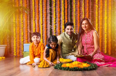 Diwali veya Rakshabandhan Kutlaması - Dört kişilik Hint ailesi Deepavali veya Bhai Dooj festivalini tatlı laddoo, yağ lambası ve şeker ve şeker kutuları ile kutluyor, yemek yiyor veya selfie çekiyor