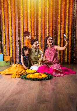 Diwali veya Rakshabandhan Kutlaması - Dört kişilik Hint ailesi Deepavali veya Bhai Dooj festivalini tatlı laddoo, yağ lambası ve şeker ve şeker kutuları ile kutluyor, yemek yiyor veya selfie çekiyor
