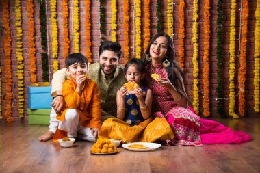Diwali veya Rakshabandhan Kutlaması - Dört kişilik Hint ailesi Deepavali veya Bhai Dooj festivalini tatlı laddoo, yağ lambası ve şeker ve şeker kutuları ile kutluyor, yemek yiyor veya selfie çekiyor