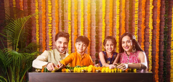 インドの家族の照明やディワリ祭の夜にオイルランプやディヤをフラワーランゴリの周りに配置 — ストック写真