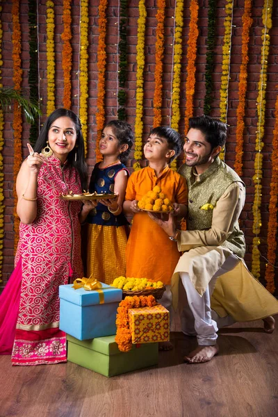 Diwali或Rakshabandhan Celebration 印度的一家四口庆祝Deepavali或Bhai Dooj节 带着甜菜 油灯或Diya和礼品盒 吃东西或自拍 — 图库照片