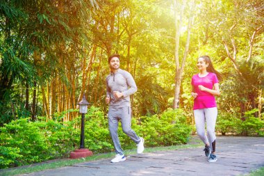 Hintli genç çift parkta ya da doğada koşuyor, koşuyor, egzersiz yapıyor ya da esniyor.