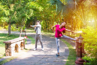 Hintli genç çift parkta ya da doğada koşuyor, koşuyor, egzersiz yapıyor ya da esniyor.