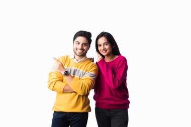 Asyalı Hintli çift, beyaz arka planda tek başlarına duran renkli ve kalın kazaklar ya da yünlü kış giysileri giyerler.