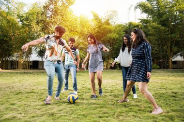 Hintli genç arkadaşlar parkta futbol ya da futbol oynuyorlar ve eğleniyorlar.