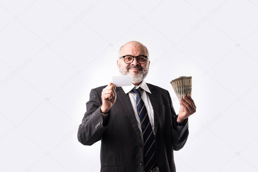 Indian asian senior businessman holding debit or credit card with currency notes or money fan