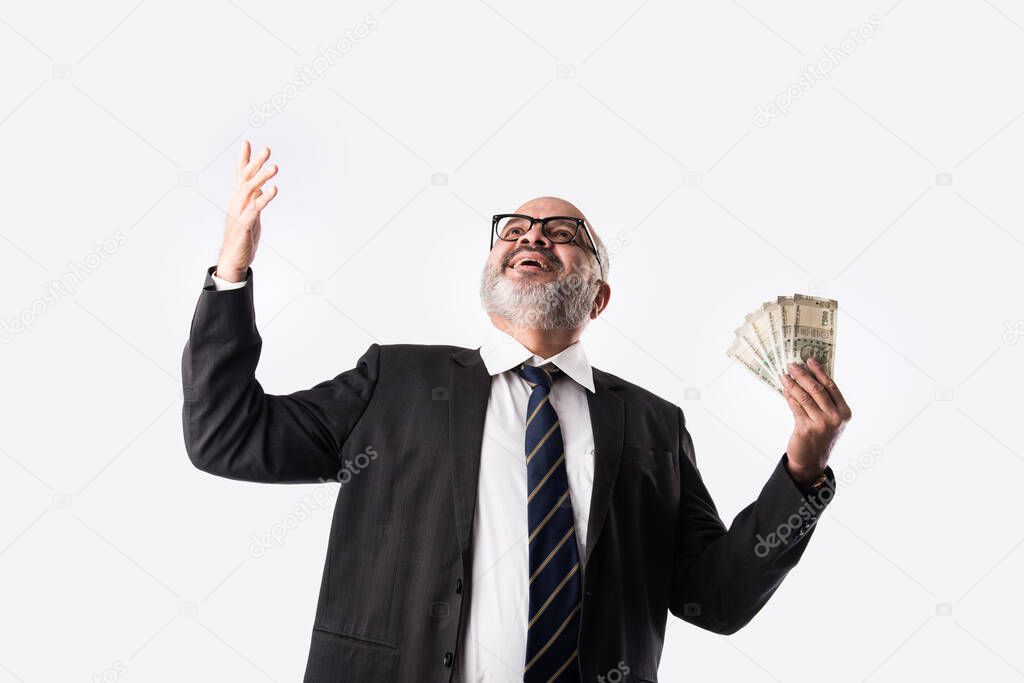 Portrait of happy Indian asian senior businessman holding indian currency notes of five hundred denominations