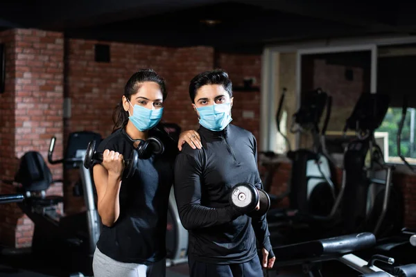 gym after corona - Indian young couple working out in gym post corona outbreak, wears protective face mask