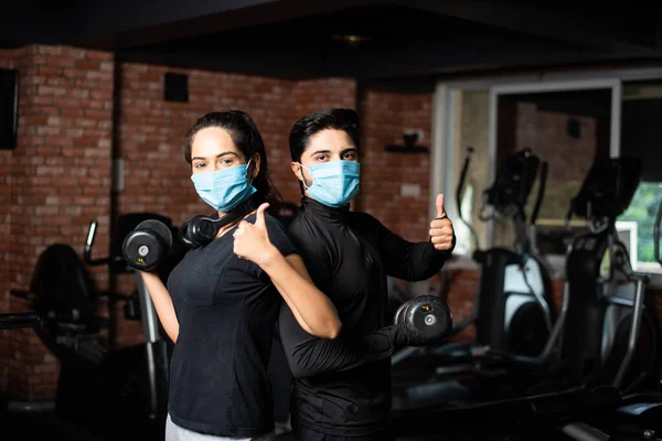 gym after corona - Indian young couple working out in gym post corona outbreak, wears protective face mask