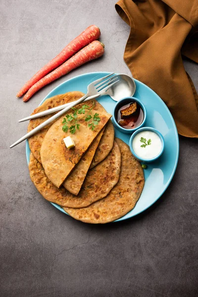Carrot or gajar ka paratha is a Punjabi dish which is an Indian unleavened flatbread made with whole wheat flour and carrot. Served with ketchup and curd
