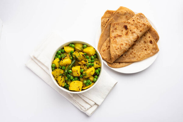 Aloo Mutter or Matar aalu dry sabzi, Indian Potato and green Peas fried together with spices and garnished with coriander leaves. served with roti or chapati