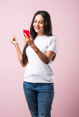 Pembe stüdyoda izole edilmiş bir Hintli kız cep telefonundan mesaj atıyor ya da kablosuz bağlantı ile akıllı telefon kullanıyor.