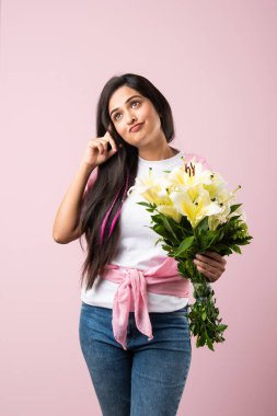 Çekici bir Hintli kadının portresi. Elinde çiçek buketi var. Pembe arka planda tek başına duruyor.