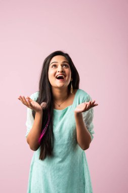 Hintli güzel kız ya da genç kadının üzerine pembe arka planda parıltı düşüyor.