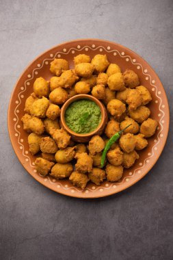 Muson Özel Moong Dal Vada, Pakoda, Dalwada, Pakora veya Mungdal Bhajiya veya Yeşil Chutney ile servis edilen Sarı Börek. seçici odak