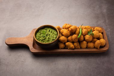 Muson Özel Moong Dal Vada, Pakoda, Dalwada, Pakora veya Mungdal Bhajiya veya Yeşil Chutney ile servis edilen Sarı Börek. seçici odak