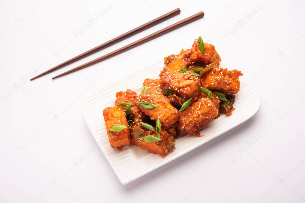 Crispy chilli paneer is a Indo Chinese starter or appetizer made by tossing fried cottage cheese in sweet sour and spicy chilli sauce, served in a plate. selective focus