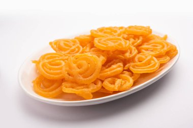 Gevrek tatlı jalebi, jilapi, zulbia, mushabak veya zalabia in white oval plaka. seçici odak