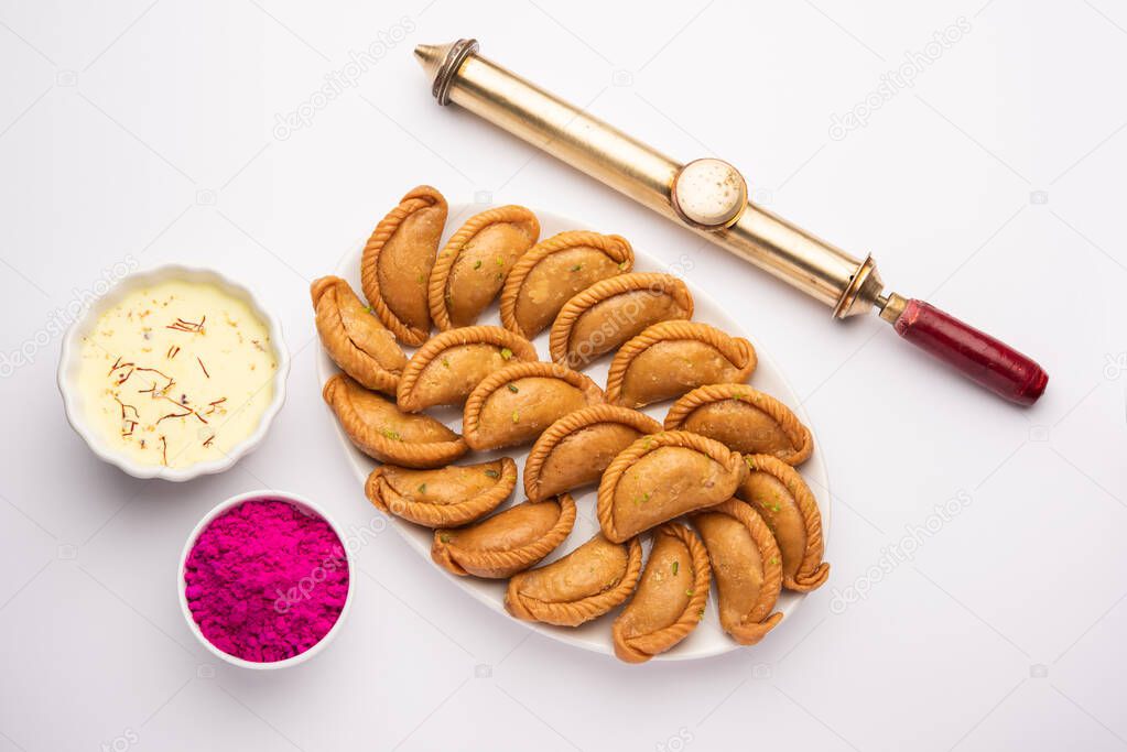 Happy Holi greeting card - Sweet Gujiya or Gujia with Thandai drink and gulal colour arranged over white background