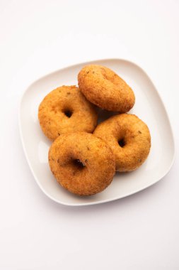 Güney Hindistan Vada, Medu Vada ya da tabakta veya kasede dal vadai, sade arka planda izole edilmiş, seçici odaklı