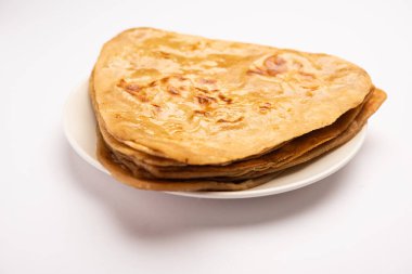 Üçgen şekilli düz paratha veya Parantha, kepekli buğday unundan yapılmış lezzetli Hint düz ekmeğidir. Bir tabakta servis edilir, seçici bir odak
