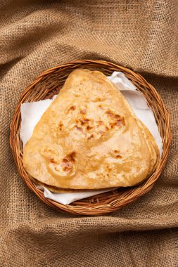 Üçgen şekilli düz paratha veya Parantha, kepekli buğday unundan yapılmış lezzetli Hint düz ekmeğidir. Bir tabakta servis edilir, seçici bir odak