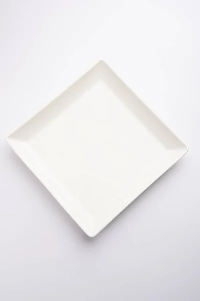 白色底座上孤立的空白白色陶瓷正方形板 — 图库照片