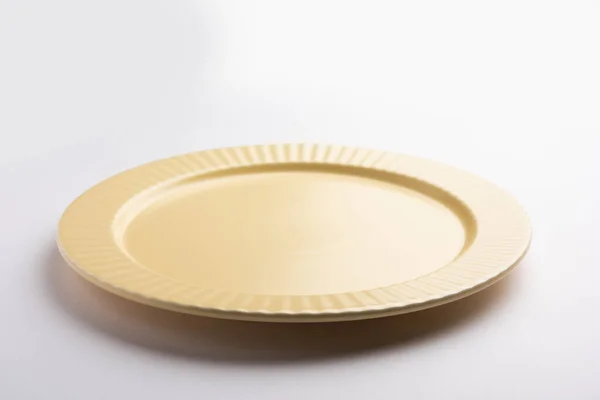 白色底座上有装饰边框的空黄色陶瓷圆盘 — 图库照片