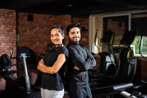 Indian asian Young couple is working out in the gym. Attractive woman and handsome fit man are training in modern gym - health and fitness concept