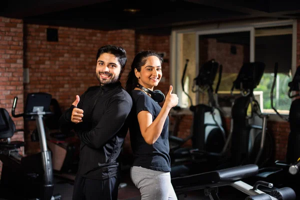 Indian asian Young couple is working out in the gym. Attractive woman and handsome fit man are training in modern gym - health and fitness concept