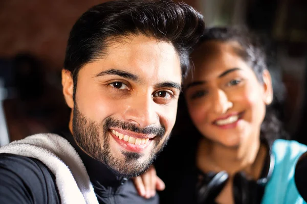 Hintli genç çift spor salonunda çalışıyor. Çekici kadın ve yakışıklı erkek modern spor salonunda eğitim görüyor - sağlık ve spor konsepti