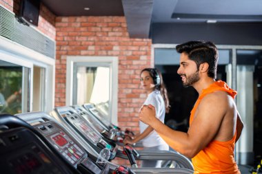 Hintli çekici çift fitness merkezinde ya da spor salonunda kardiyo eğitimi yapıyor, seçici odaklar - sağlık ve fitness konsepti